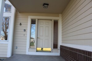 A front door with a small window above it, a mailbox, and a brick wall to the right. - The Johnston Paradise (Johnston)