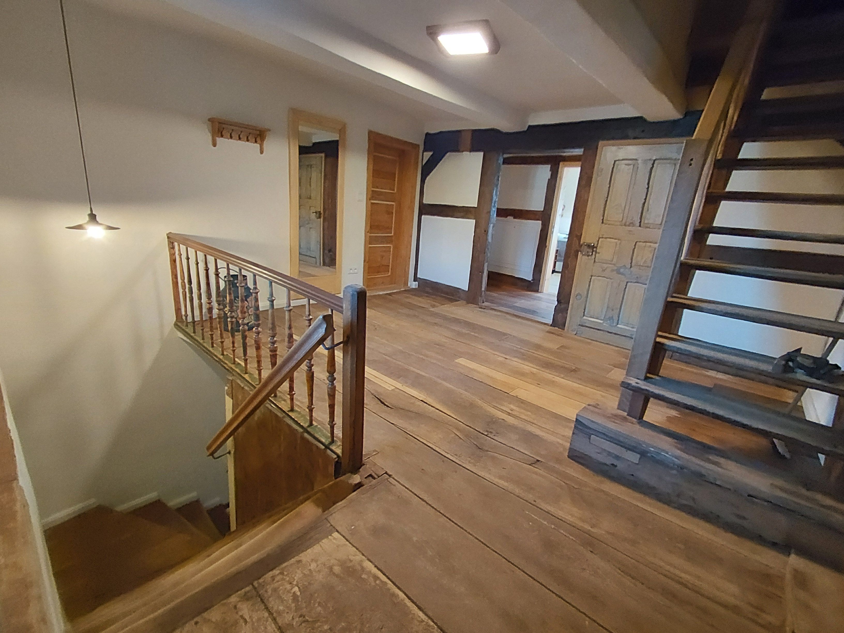A wooden staircase with a handrail leading to an upper floor.
