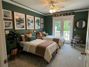 A bedroom with two beds, a ceiling fan, artwork on the wall, and a view through a glass door. - Waterfront Coastal Charm yet close to the Surf @ 369ChapelLane (Myrtle Beach)
