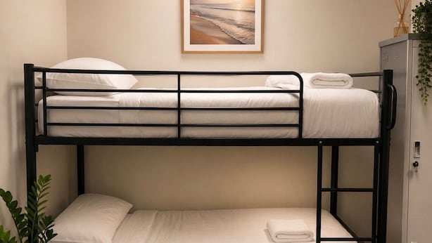 A bunk bed room with a framed picture on the wall, a small cabinet, and a woven rug on the floor. - Brunsi hostel (Brunswick)
