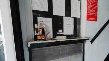 Un comptoir d’accueil d’hôtel avec divers avis affichés et un panneau indiquant le mot de passe du réseau Wi-Fi.