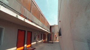 Un callejón estrecho con un edificio que tiene una puerta roja y una escalera que sube a un nivel superior.