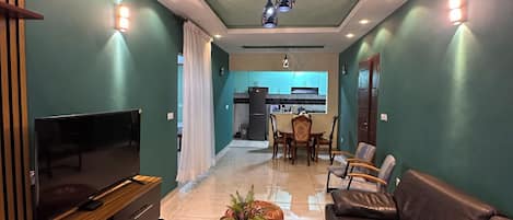 A modern living room with a flat-screen TV, leather sofa, and a coffee table with a plant.