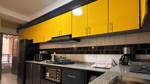 Cozinha com armários amarelos, pia de aço inoxidável e micro-ondas.