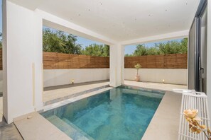 Ein moderner Pool im Freien mit Holzzaun und Blumentopf.