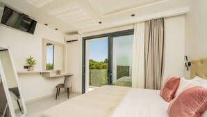 Quarto moderno com cama grande, televisão na parede, escrivaninha com cadeira e porta de vidro deslizante para uma varanda.