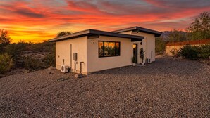Une maison moderne à deux étages, dotée d’une allée en gravier et entourée d’une végétation désertique.