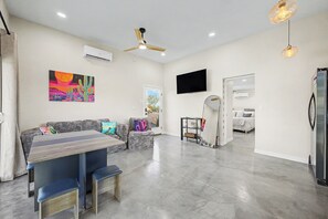 Uma sala de estar moderna com sofá, mesa de jantar e ventilador de teto.