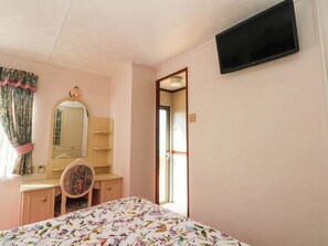 A bedroom with a bed, a desk, a chair, a mirror, and a television mounted on the wall. - Buzzards Retreat (Wrexham)