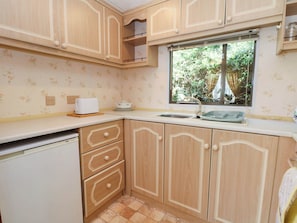 Cocina con alacenas de madera, una ventana, un lavamanos y un tostador.