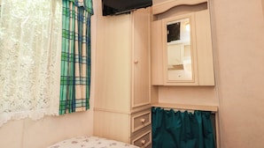 A bedroom with a bed, a wardrobe, a mirror, and curtains.