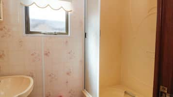 A bathroom with a sink, a window with a curtain, and a bathtub.