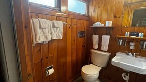 Et badeværelse med træpaneler, toilet, vask og håndklædetørrestativ.