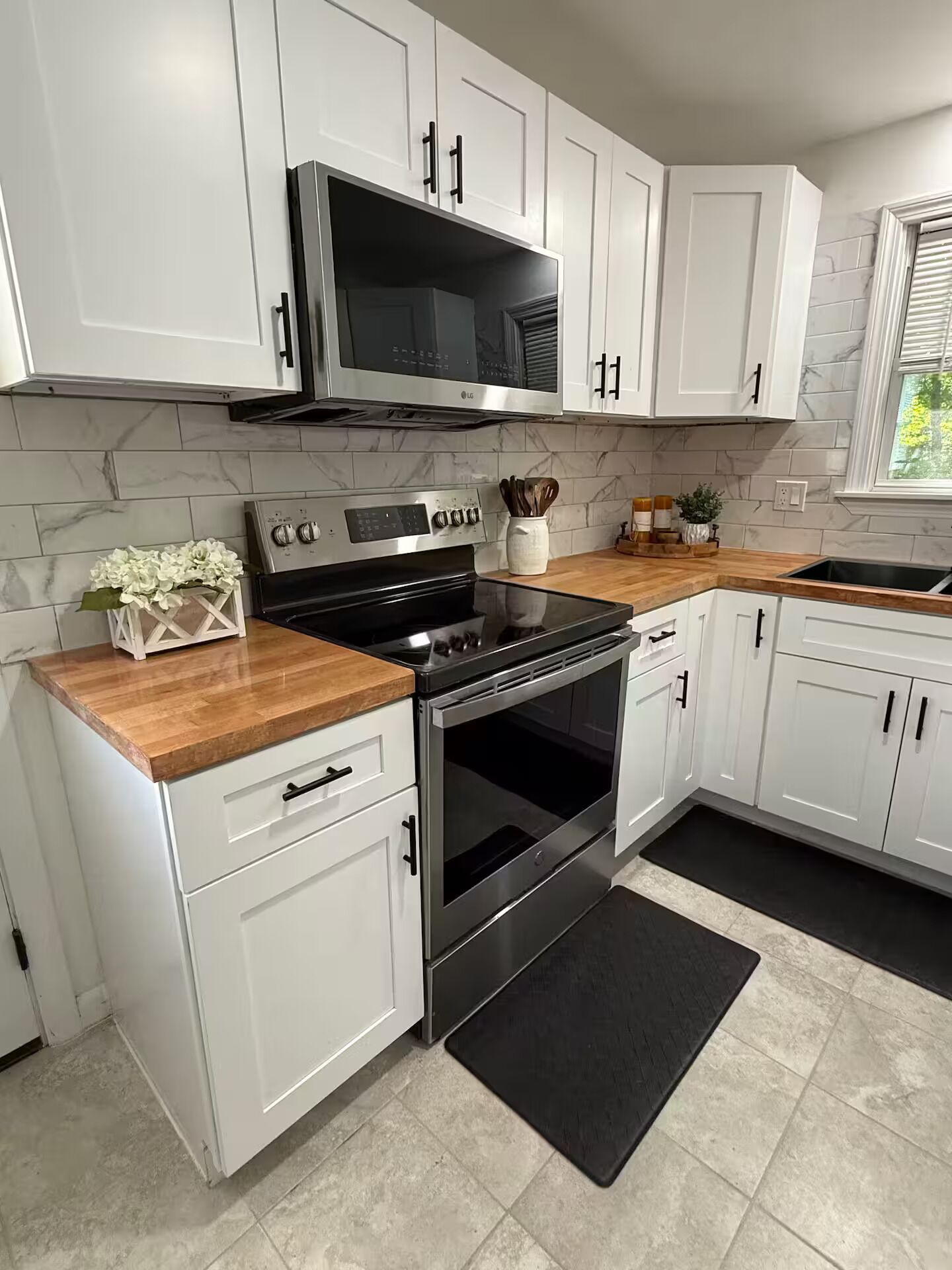 A modern kitchen with white cabinets, a stainless steel stove, and a black countertop.