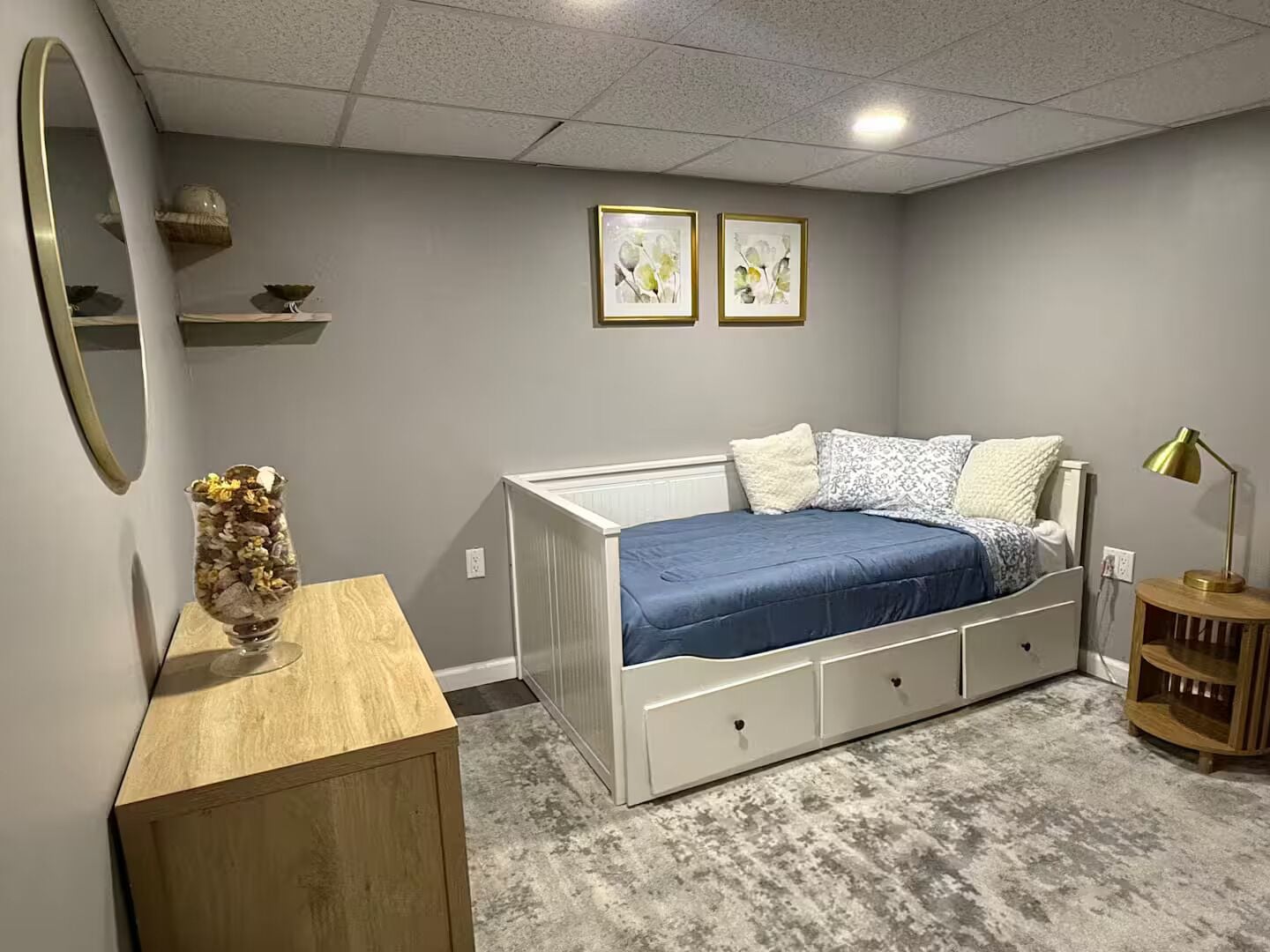 Ein Schlafzimmer mit einem Bett, einem Nachttisch, einer Lampe und zwei gerahmten Bildern an der Wand.
