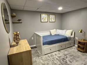 A bedroom with a bed, a bedside table, a lamp, and two framed pictures on the wall. - Red Door Retreat (Vernon)