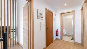 A hallway with wooden flooring, a fire extinguisher, and a framed picture on the wall.