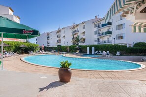 Ein Poolbereich mit Liegestühlen und einem Sumol-Sonnenschirm.