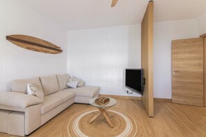 Un salon avec un canapé, un téléviseur, une porte en bois et une table basse ronde.