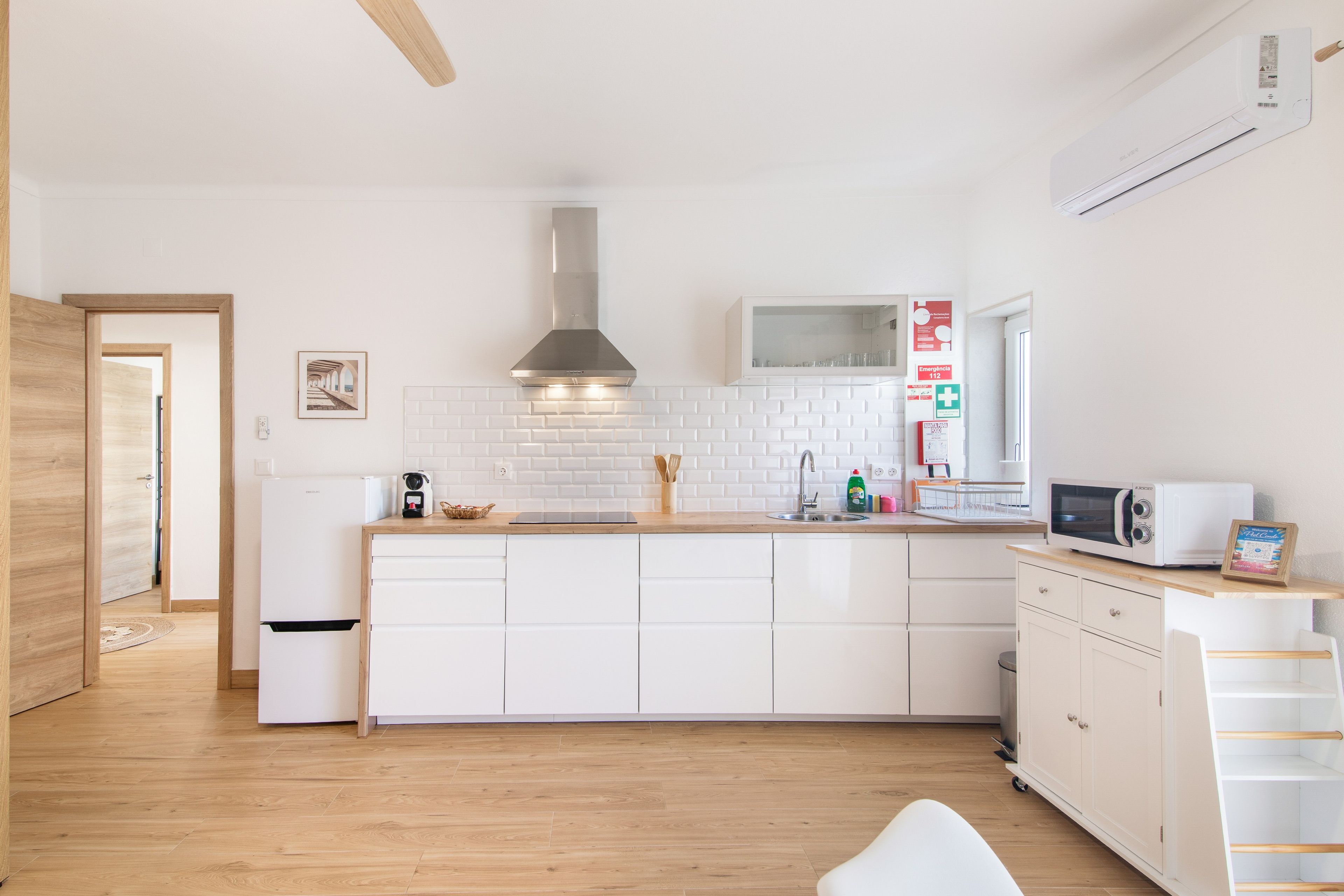 A modern kitchen with white cabinetry, a stainless steel range hood, and a built-in microwave.