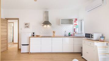 A modern kitchen with white cabinetry, a stainless steel range hood, and a built-in microwave.