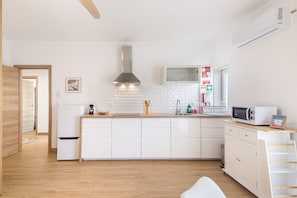 A modern kitchen with white cabinetry, a stainless steel range hood, and a built-in microwave. - Pool Apartment with Shared Pool, Private Terrace, and Wi-Fi (Tavira)