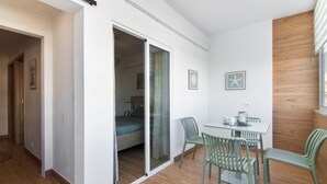 Ein modernes Zimmer mit einem Bett, einem Esstisch mit Stühlen und einer Glastür, die in einen weiteren Raum führt.