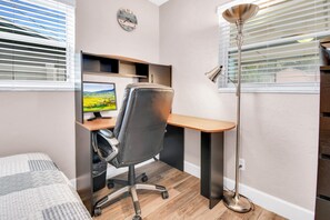 A modern office space with a desk, chair, computer, and a standing lamp. - 2-bedroom house in adorable Largo with cool AC and charm (Largo)