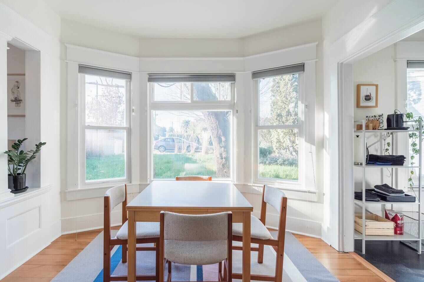 Un comedor con mesa y sillas de madera, ventanas amplias y vistas al exterior.