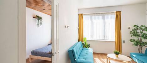 A modern living room with a sofa, a small table, and a window with curtains.