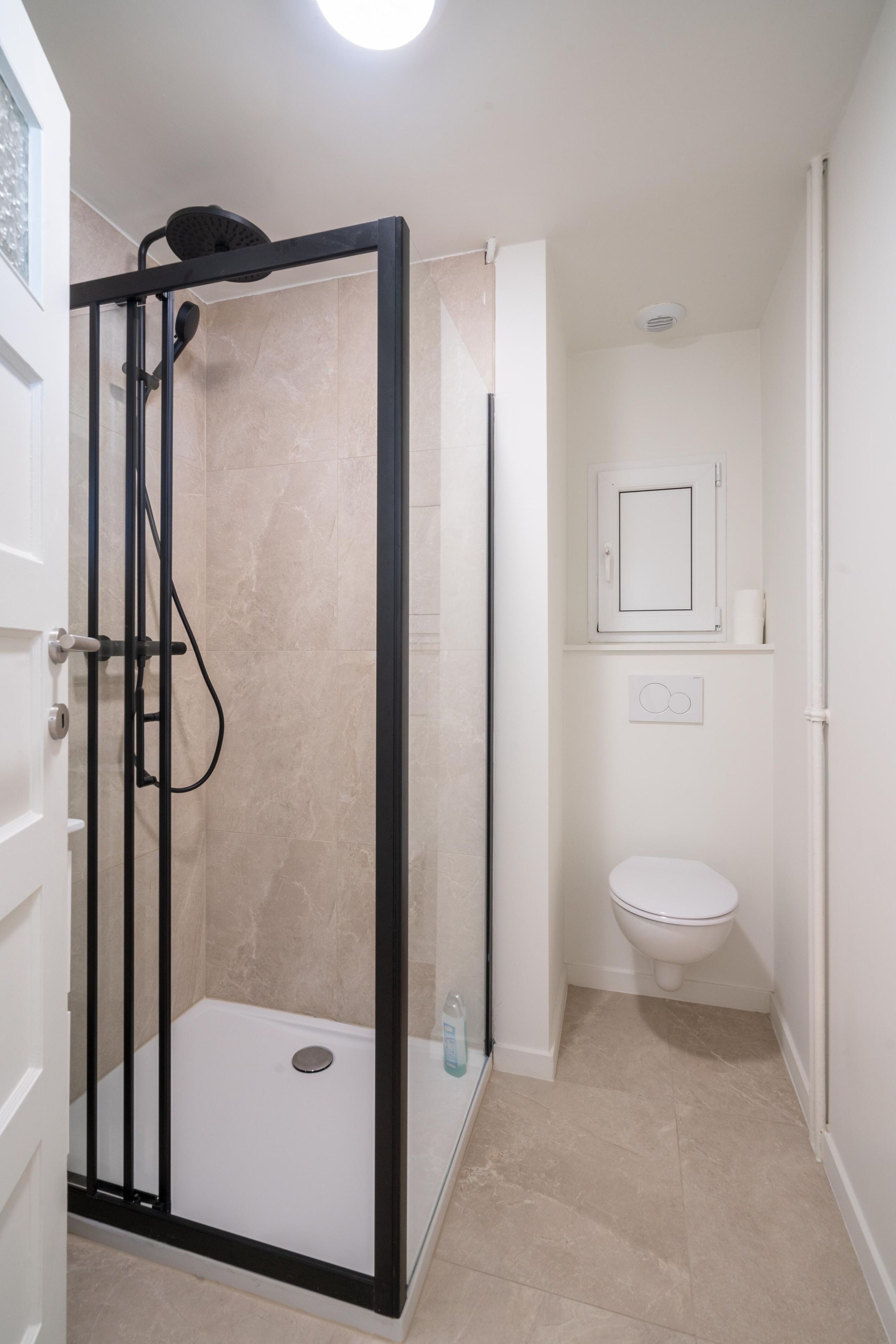 Un baño con cabina de ducha, inodoro y espejo.