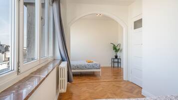 Un dormitorio con una cama, un radiador, una planta en maceta y vistas de la ciudad a través de una ventana.
