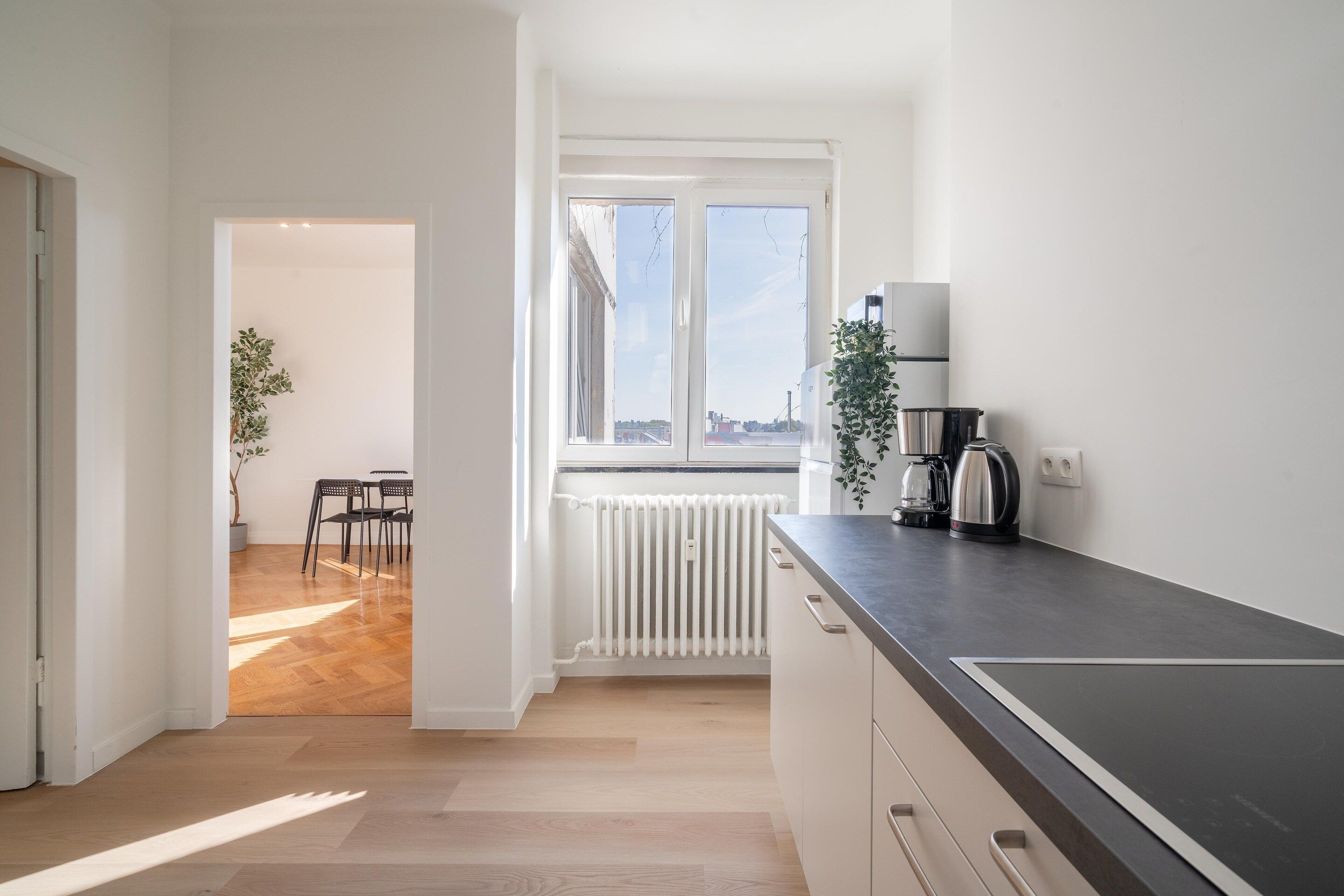 Eine moderne Küche mit schwarzem Arbeitsplatz, einer Kaffeemaschine und einer Heizung.