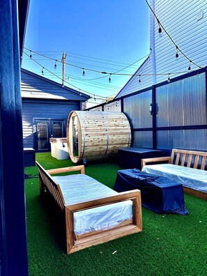 A rooftop lounge with artificial grass, wooden furniture, and string lights. - Luxury & Wellness (Dayton)