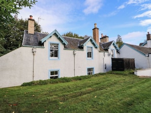 A traditional house with a white exterior, multiple chimneys, and a grassy yard.
