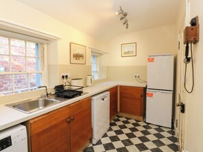 Una cocina compacta con un lavamanos, lavavajillas, refrigerador y piso a cuadros.