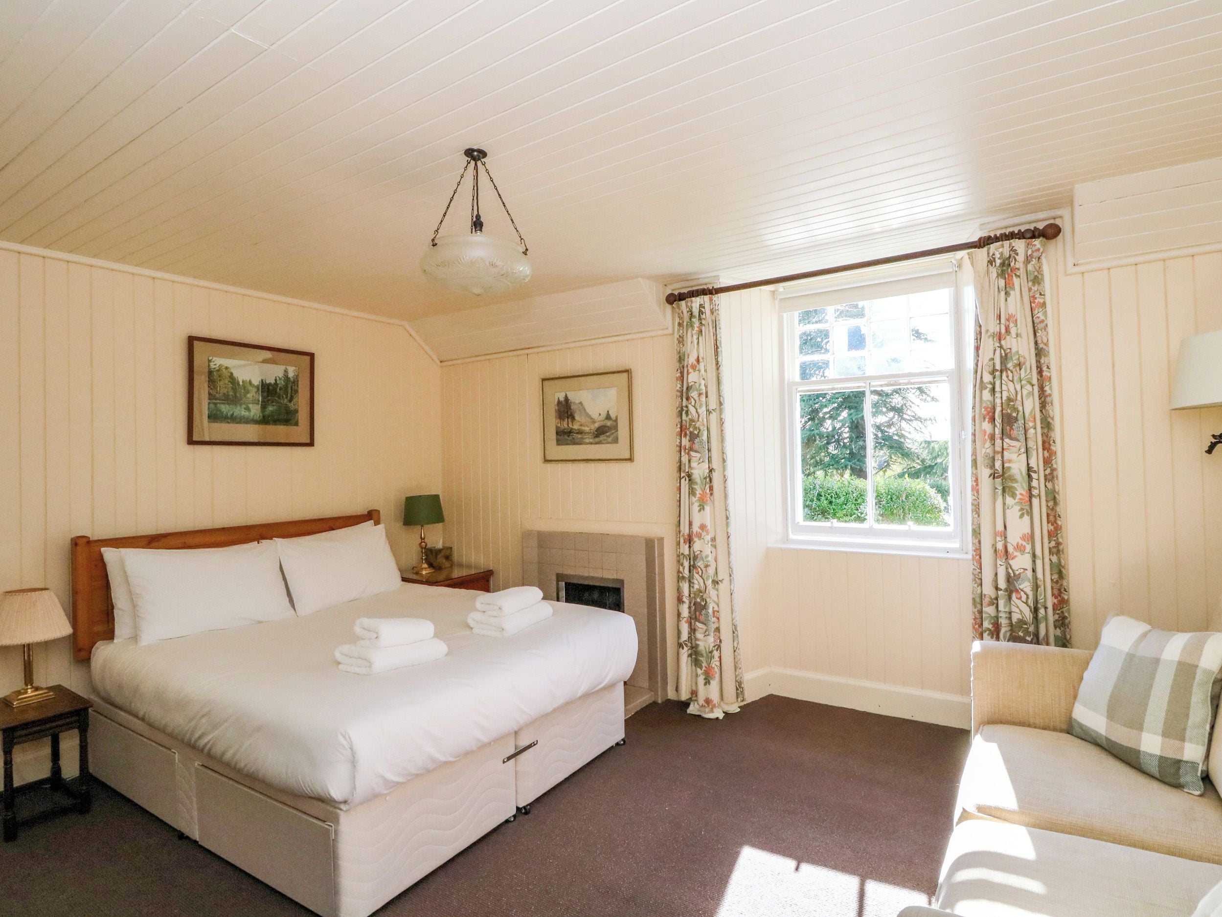 Una habitación de hotel con cama, chimenea, sofá y ventana con cortinas.