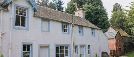 A two-story house with a white exterior and blue trim, a chimney, and a gravel driveway.