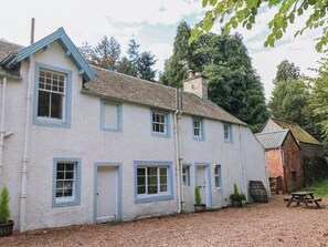A two-story house with a white exterior and blue trim, a chimney, and a gravel driveway.