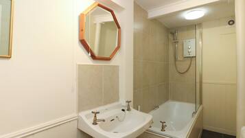 A bathroom with a sink, mirror, shower, and bathtub.