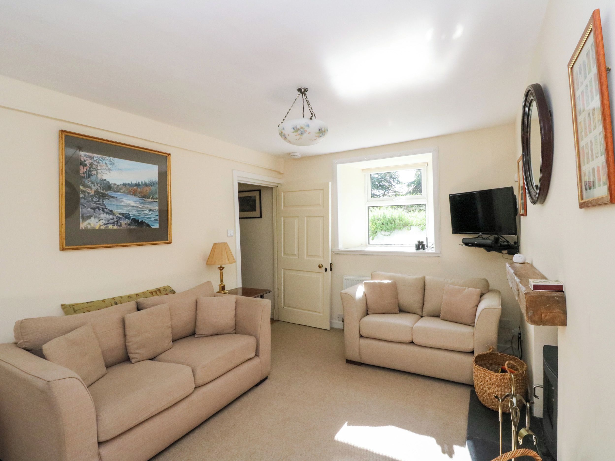 A living room with two sofas, a painting, a television, and a fireplace.