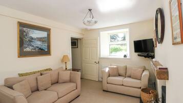 A living room with two sofas, a painting, a television, and a fireplace.