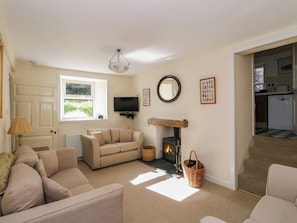 A cozy living room with a sofa, a fireplace, a television, and a window.