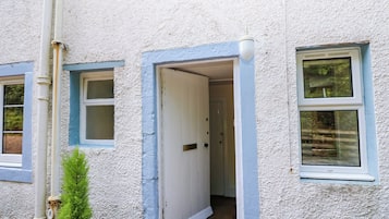 Un bâtiment à l’extérieur blanc, avec une porte et une fenêtre.