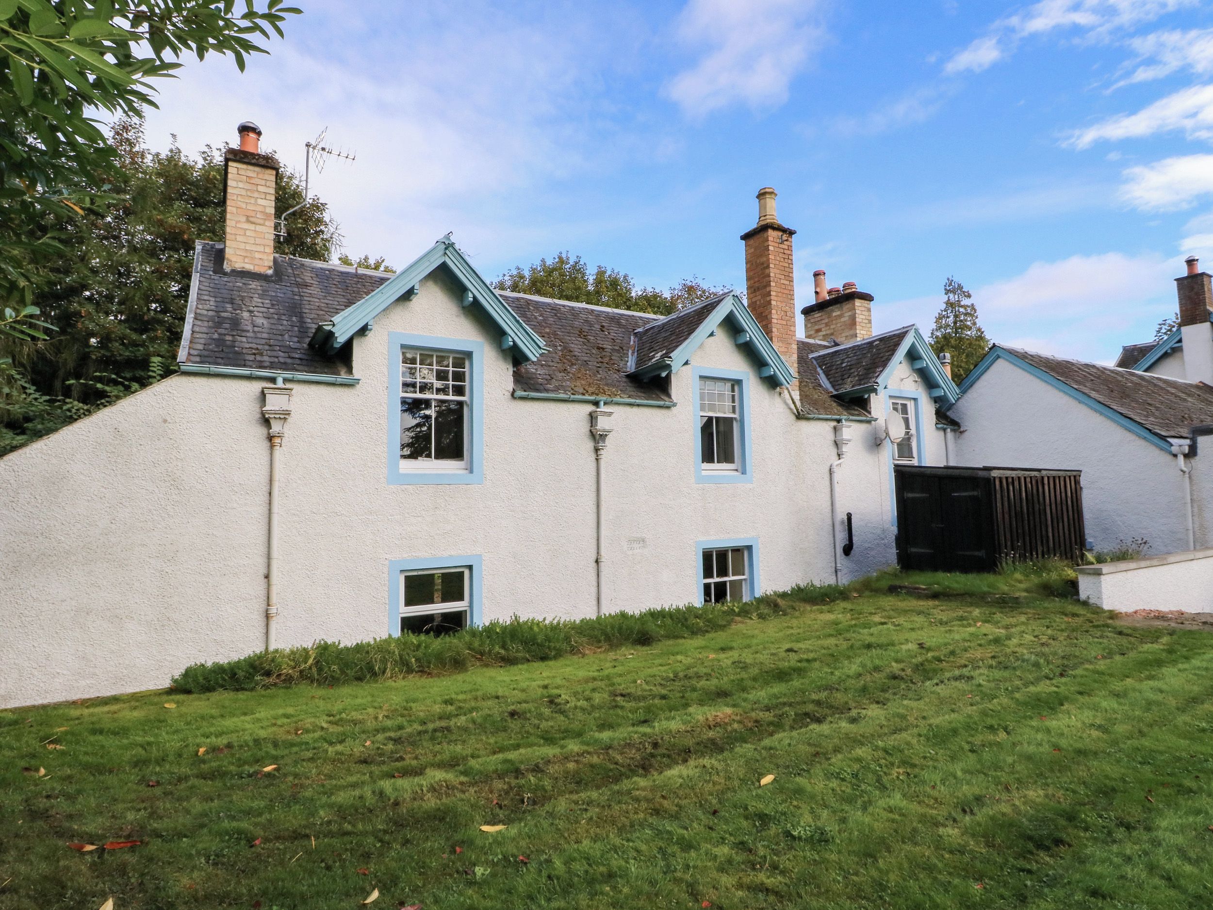 A traditional house with a white exterior, multiple chimneys, and a grassy yard.