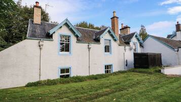 A traditional house with a white exterior, multiple chimneys, and a grassy yard.