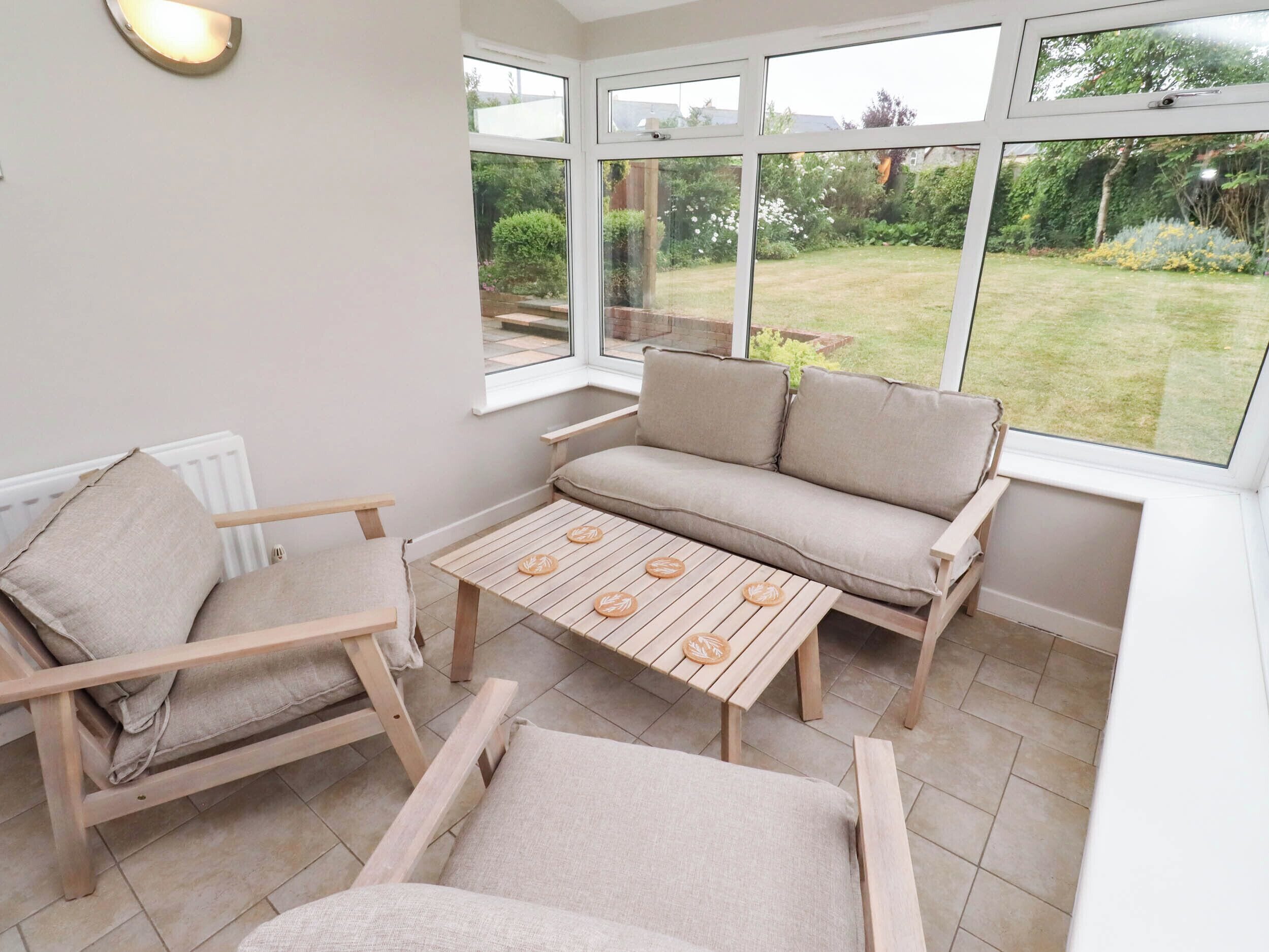 A conservatory with a sofa, chairs, and a table.