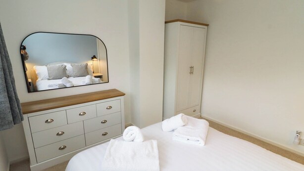 Ett hotellrum med en säng, en byrå, en spegel och en garderob.