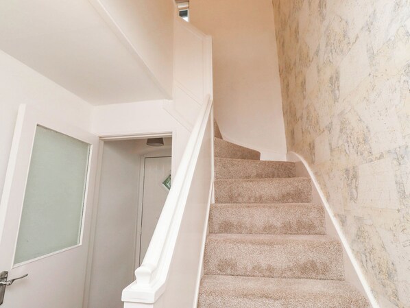 Eine Treppe mit Teppich und einer weißen Wand mit Marmorstruktur.