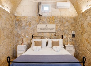 Ein Schlafzimmer mit einer Steinwand, einem Bett mit weißer Bettwäsche, zwei Nachttischen und einem Schild über dem Bett.